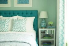 a retro-inspired aqua bedroom with a turquoise upholstered bed and printed bedding and a rug, a nightstand with books