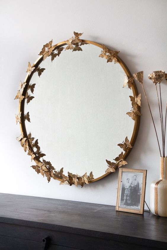 a round mirror in a gilded frame with butterflies is a super chic and cool decoration for any space, it looks very sophisticated