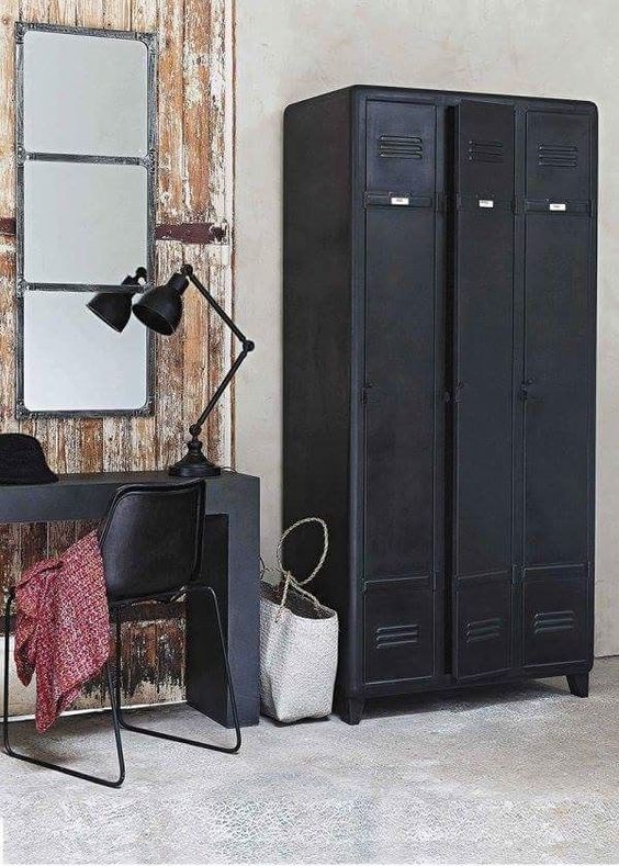 a shabby chic meets industrial space with black lockers, a black desk and chair, a black lamp and a mirror is a cool and lovely space
