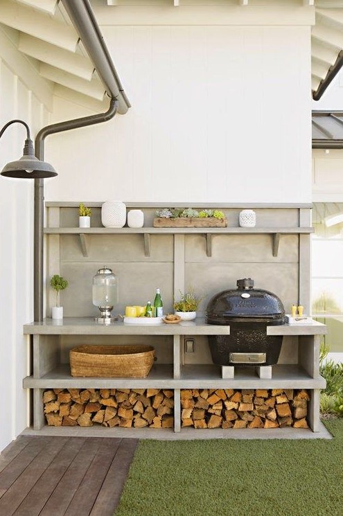 a simple and comfortable outdoor bqq zone with a grill, some cooking space and firewood stored