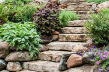 a sloped garden with stone steps and greenery and bold blooms lining them up looks lovely and chic