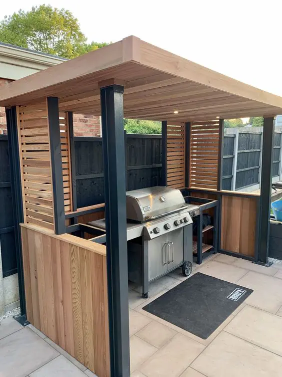 a small and cool outdoor bbq area wiht a roof over the space, a grill and some shelves and nothing else is laconic and cool