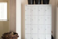 a small and cozy entryway with a set of white lockers, some baskets and a vintage suitcase for storage is cool