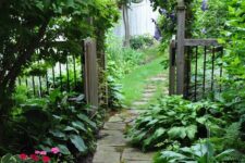 a small secret garden with a stone garden path, greenery and bold blooms is a lovely space that feels fairy-tale-like