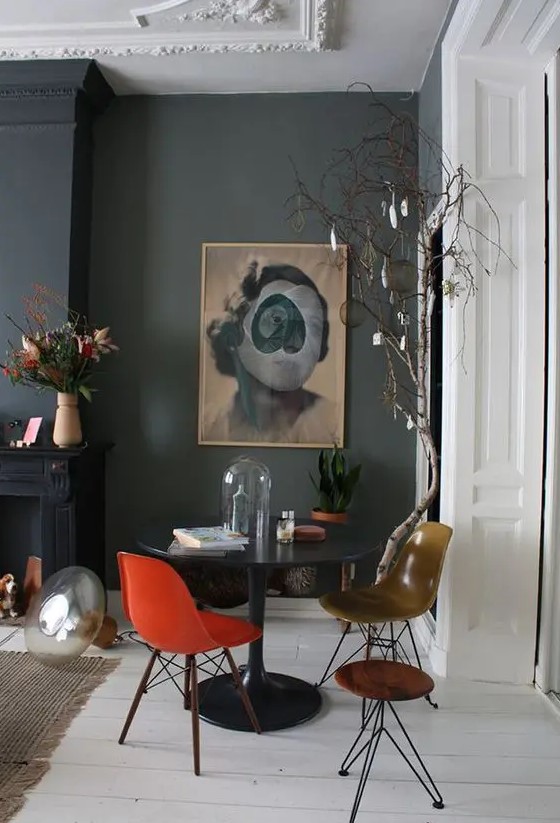 a sophisticated and dramatic space with a black table, an orange and mustard Eames chair, black walls and a fireplace
