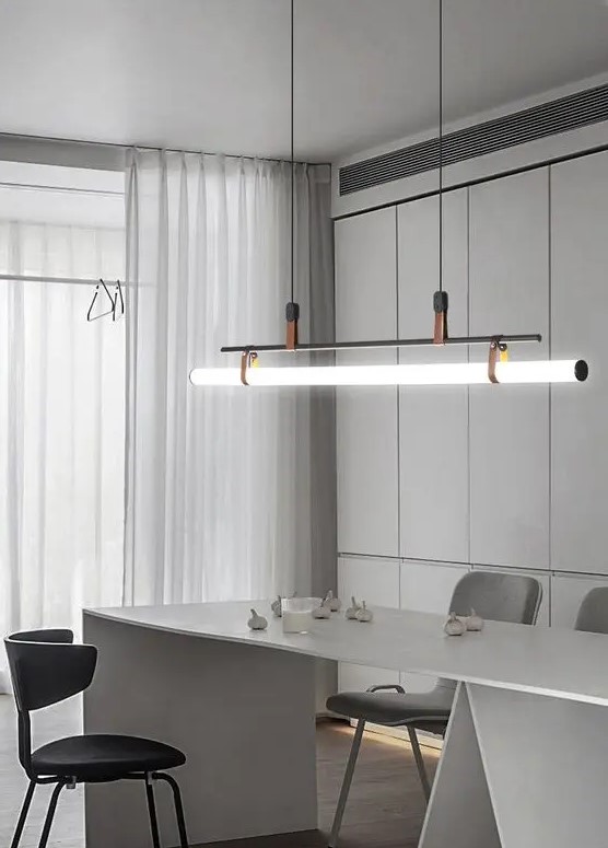 a sophisticated minimalist dining space with a sleek storage unit, a large neutral dining table, grey and black chairs and a pendant lamp