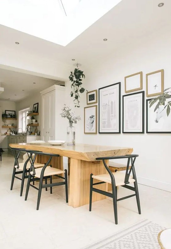 a sophisticated modern dining space with a large stained table, black wishbone chairs, a gallery wall and potted greenery