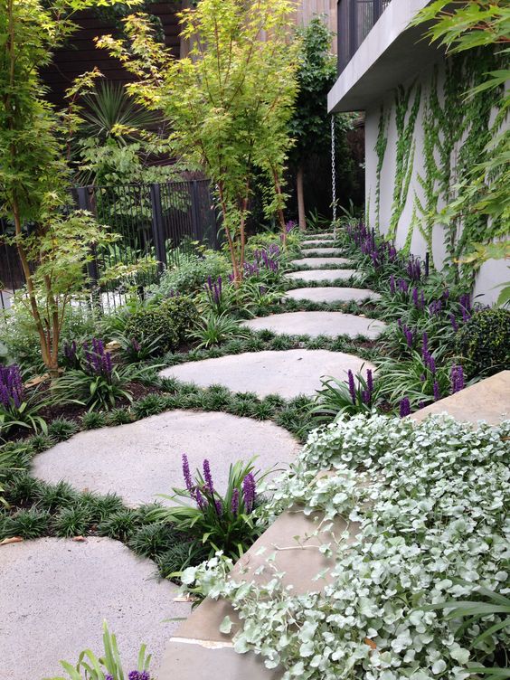 a stone garden path with large rocks, greenery and grasses in between, is a cool and bold solution for a modern space