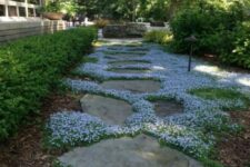 a stone garden path with white blooms and greenery in between looks very chic and very inspiring