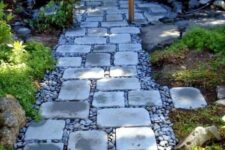 a stylish and comfrotable garden path of pebbles and simple stones contrasts the greenery around
