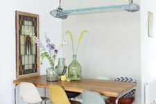 a stylish dining space with a long dining table, colorful Eames chairs, a mosaic artwork and a catchy lamp on chain
