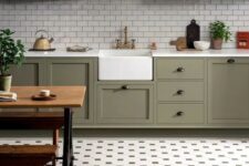 a stylish farmhouse olive green kitchen with white subway tiles and a pretty tile floor plus a rustic dinign set is wow