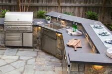 a stylish outdoor grill space with a large stone clad unit with a grill, a sink and some countertops for cooking is awesome