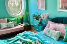 a super bright and quirky bedroom with turquoise walls, a radiator and a nightstand, an oval window, a pink daybed with colorful pillows, a black bed with bright turquoise and pink bedding