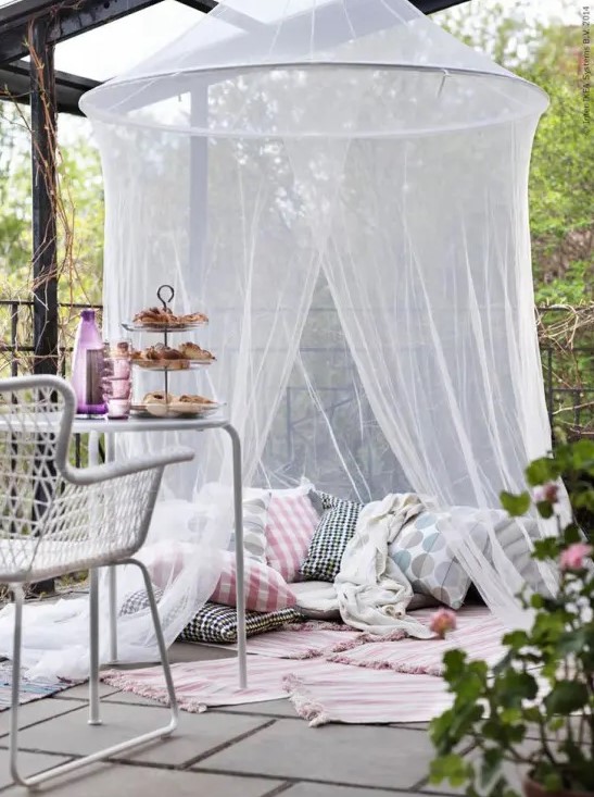 a terrace with a pillow space with rugs and a mosquito net over   invite your kids to spend time there without any bugs