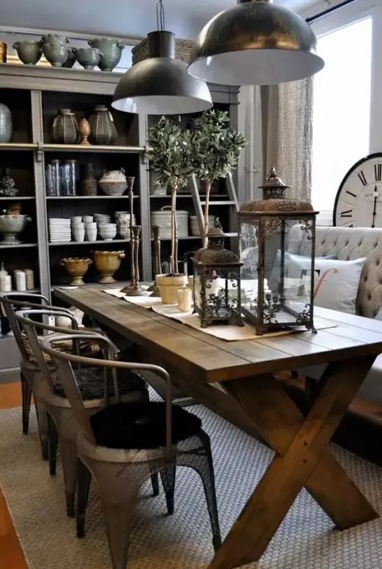 a vintage rustic dining space with a large buffet, a stained trestle table, metal chairs, a tufted sofa and pendant metal lamps and metal lanterns
