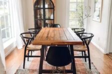 a welcoming rustic dining space with a dining table with a stained tabletop, black woven chairs, a chic chandelier and a vintage buffet
