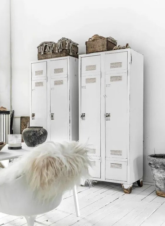 a white Scandinavian space with white lockers, a white table and a chair, some wooden crates for storage is a cool room
