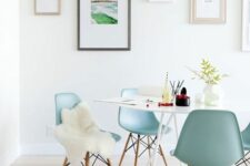 an airy dining space with a white table, light blue Eames chairs, a gallery wlal and a quirky pendant lamp is a lovely nook