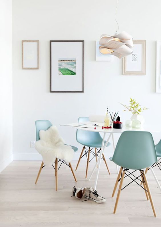 an airy dining space with a white table, light blue Eames chairs, a gallery wlal and a quirky pendant lamp is a lovely nook