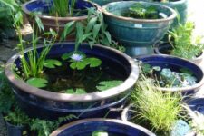 an arrangement of blue, navy, trquoise and brown bowls with water and floating greenery and plants is a cool idea for any modern outdoor space