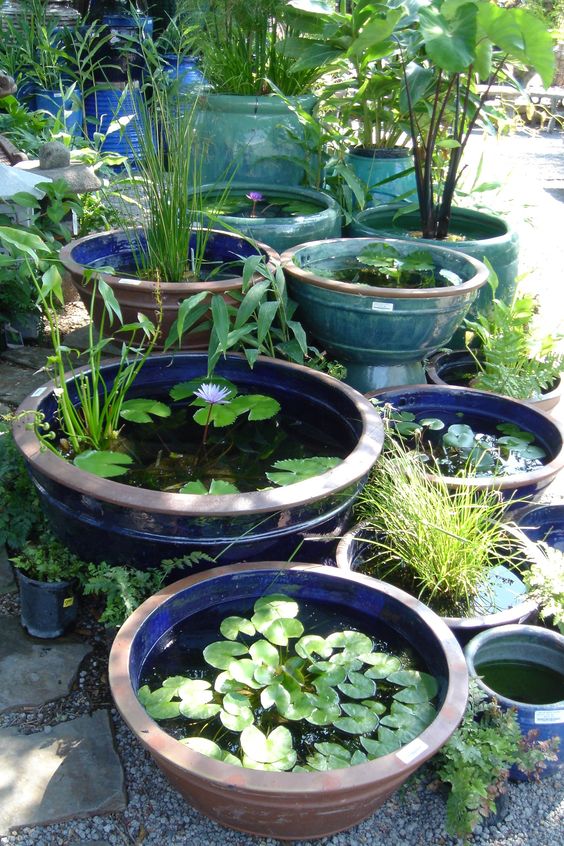 an arrangement of blue, navy, trquoise and brown bowls with water and floating greenery and plants is a cool idea for any modern outdoor space