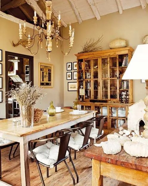 an eclectic dining room with a stained buffet, a stained dining table, metal chairs, a vintage chandelier and several gallery walls
