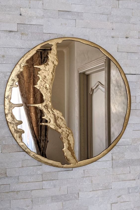 an elegant mirror in a gold frame with some detailing is a chic and cool idea to bring ultimate elegance and chic to the space