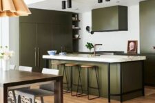 an olive green kitchen with flat panel cabinets, a large kitchen island, white and black countertops, black touches and lamps