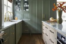 an olive green kitchen with shaker cabinets, a stained kitchen island, white stone countertops and gold fixtures