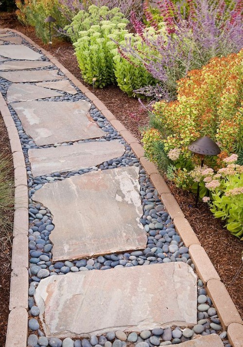 an unusual garden path made of pebbles and rough stones plus a matching border feels accurate though not too much