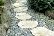 grey pebbles and rough stones and rocks that create a border of the path, a natural and fresh look for every garden