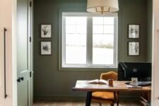 08 a farmhouse olive green home office with a wooden desk and a marigold chair, a pendant lamp and some artwork