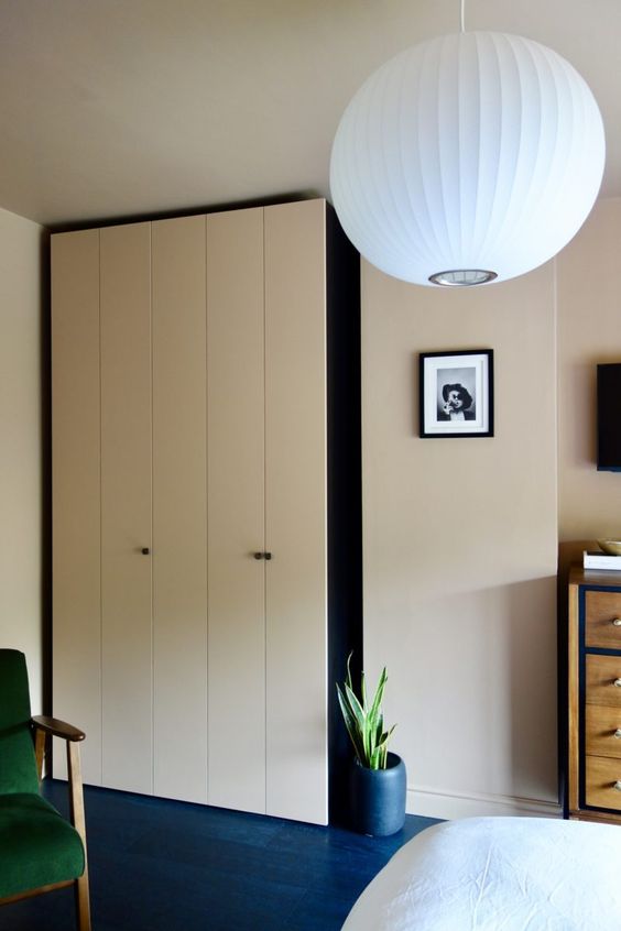 a neutral bedroom featuring a two-tone IKEA Pax wardrobe with black knobs that makes a statement in the space