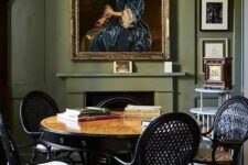20 a sophisticated dining room with olive green walls, a fireplace, a stained table, black chairs, refined lamps and artwork