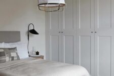 22 a neutral bedroom with built-in IKEA Pax wardrobes, a grey bed with neutral bedding, a bench and a paper pendant lamp