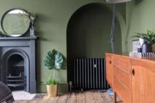 22 a vintage olive green living room with a non-working fireplace, a niche with a credenza, a stained sideboard, a grey floor lamp and a mirror