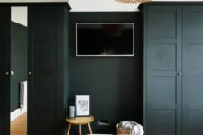 31 a stylish modern bedroom with black walls and matching black IKEA Pax wardrobes, a mirror, a stool and a TV, a pendant lamp