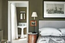 31 an olive green bedroom with a printed upholstered bed and bedding, a black and white artwork, stained furniture