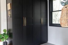 35 an elegant mudroom with black IKEA Pax wardrobes with gold handles, floral wallpaper on the ceiling and potted plants