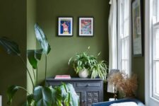 36 an olive green space with an inlay sideboard, a blue chair and an orange pouf, some bright decor and potted plants is cool