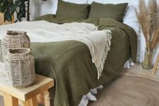 39 a boho bedroom in neutrals, with a bed done with olive green bedding, a wooden bench and woven candleholders, pampas grass, potted plants and burst mirrors