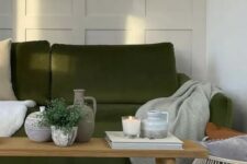 44 a Scandinavian living room with creamy paneling, an olive green sofa and neutral textiles, a wooden bench with decor