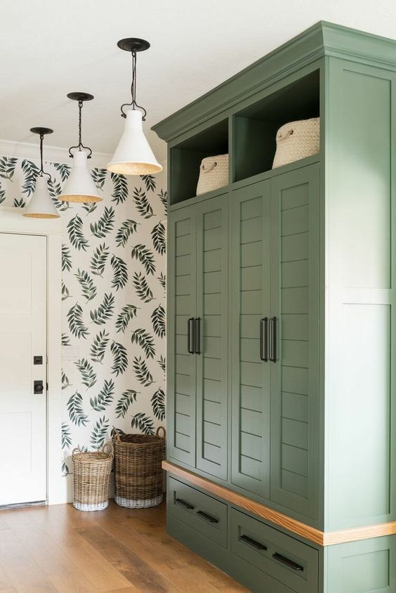 a farmhouse renovation of an IKEA Pax wardrobe, done in a soft green shade, with shiplap doors, black handles and baskets