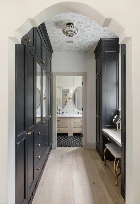 a stylish walk-in closet with built-in IKEA PAx wardrobes with elegant brass knobs and mirrors and a vanity with a stool