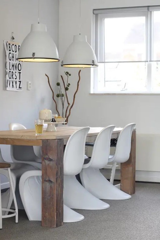 a Scandinavian dining space with a stained table, white Panton chairs, white pendant lamps and some simple decor