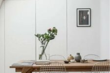 a Scandinavian dining space with skylights, a stained table, Eames wire chairs, some decor and an artwork