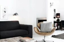 a Scandinavian living room with a black sofa, an industrial coffee table, a tan leather Swan chair and printed pillows