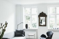 a Scandinavian living room with a neutral sofa, a black Swan chair, a white dining table and black chairs, a mirror in a vintage frame