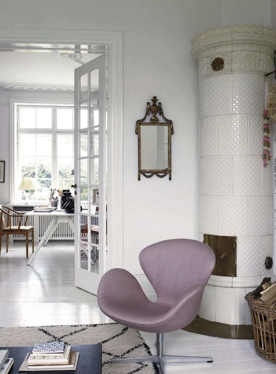 a Scandinavian nook with a white hearth, a lilac Swan chair, a vintage mirror, a basket with firewood and a coffee table